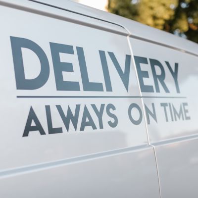 bezorgbus met de tekst 'bezorging altijd op tijd' op de zijkant in zwarte letters.