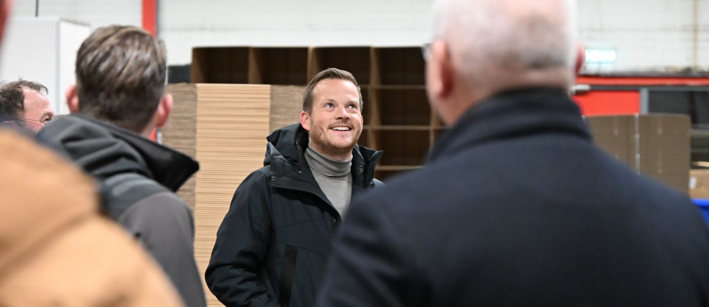Mark Doosje, managing director van Kruizinga, staat omringd door klanten in het magazijn van Kruizinga, glimlachend om zich heen te kijken terwijl hij vertelt over de groei, kennis, ervaring en betrouwbaarheid van Kruizinga.