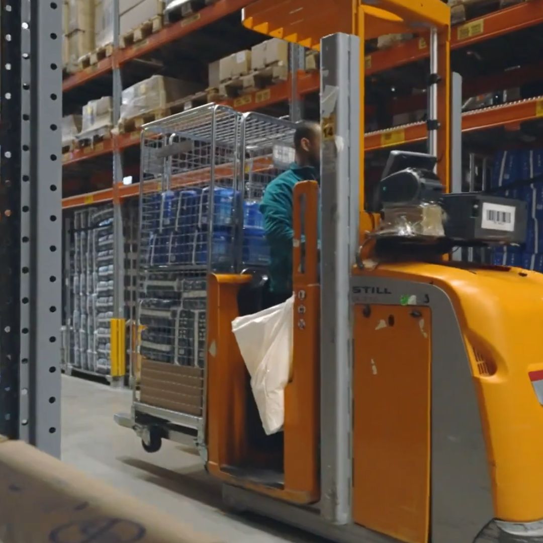 Mediq magazijnmedewerker op een heftruck die met de rolcontainers van Kruizinga orders pickt.